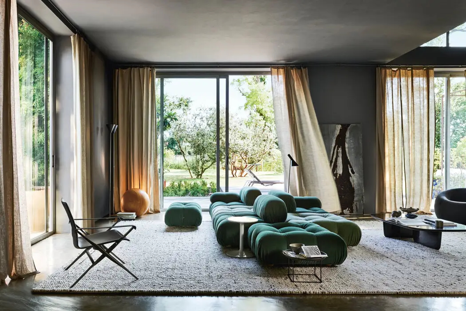 Zelena smaragdna sofa Camaleond B&B Italia u modernoj kući s velikim staklenim stijenama