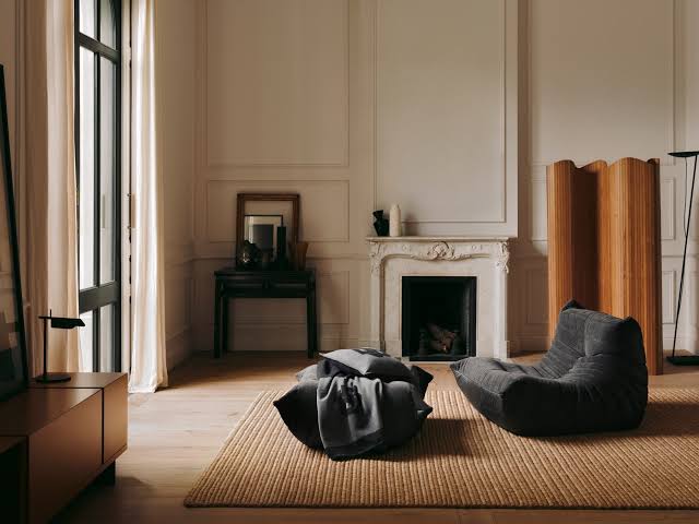 Antracit Togo sofa i tabure od Ligne Roset u skandinavskom interijeru sa štukaturama i kaminom